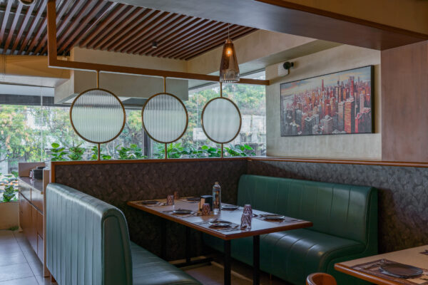 Booth seating area with green upholstery and artwork — 4 Cups Restaurant, Coimbatore