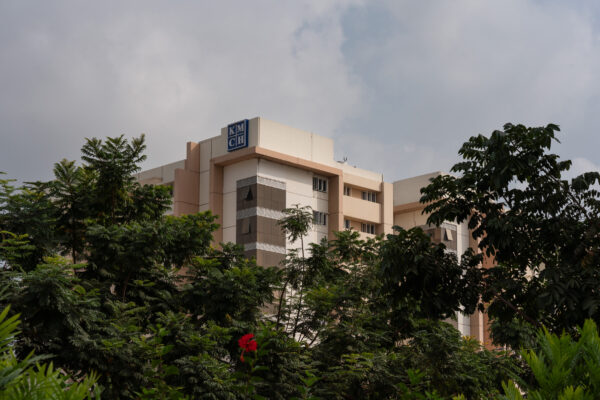 Hospital exterior surrounded by mature trees — KMCH, Coimbatore